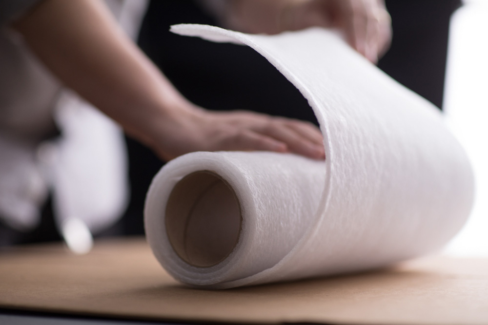 A roll of PE foam is being opened on a flat surface.